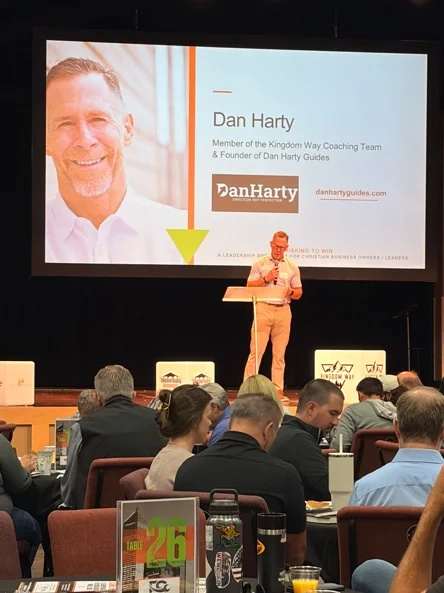 Dan Harty speaking on stage to a room of leaders